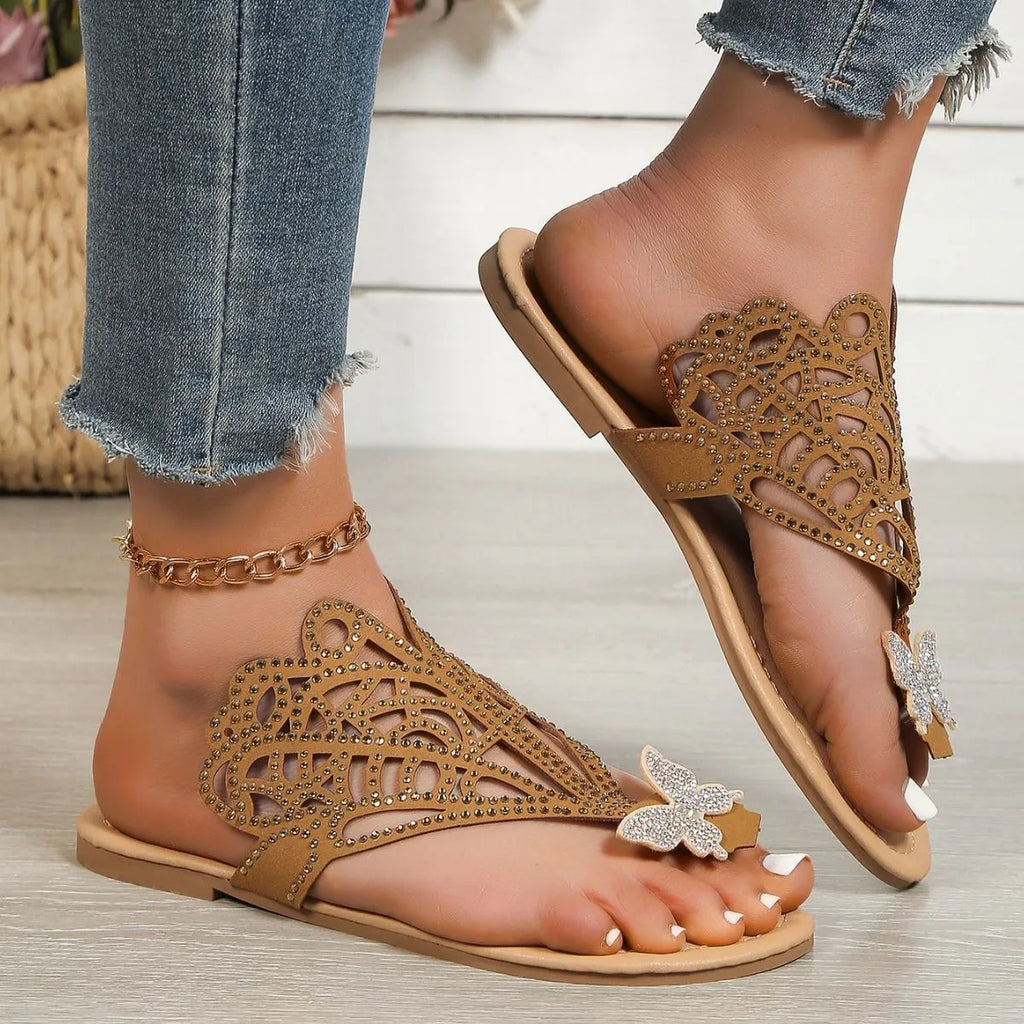 Women's black slip-on sandals with rhinestone accents and flip-toe design showing rubber sole