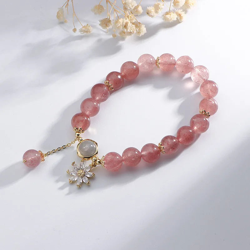 Mori style crystal bracelet with strawberry quartz stones and floral design details on a wrist.