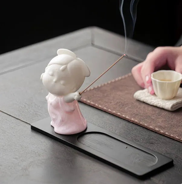 Ceramic cute female court attendant incense burner decoration in hand-painted colours on a shelf.