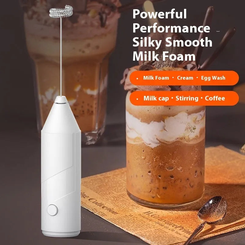 Compact black handheld milk frother with stainless steel whisk on a kitchen counter.