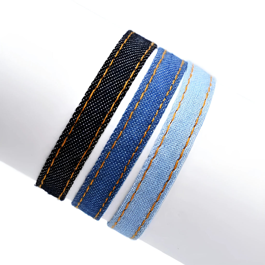 Handmade denim fabric bracelet carrying strap in national style on wrist, showing charm attachment point.