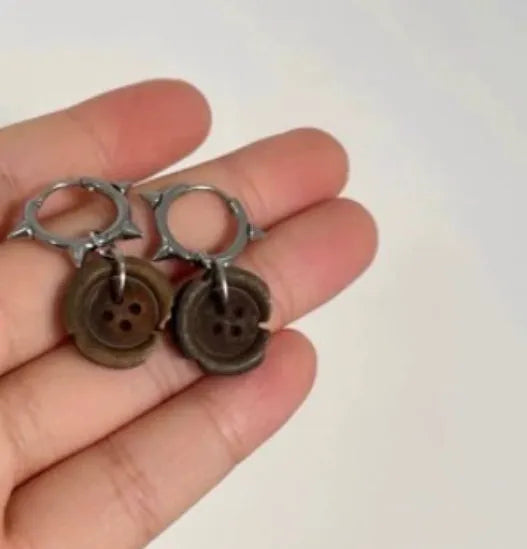 One pair of brown alloy ancient style burned gap button distressed earrings on neutral background