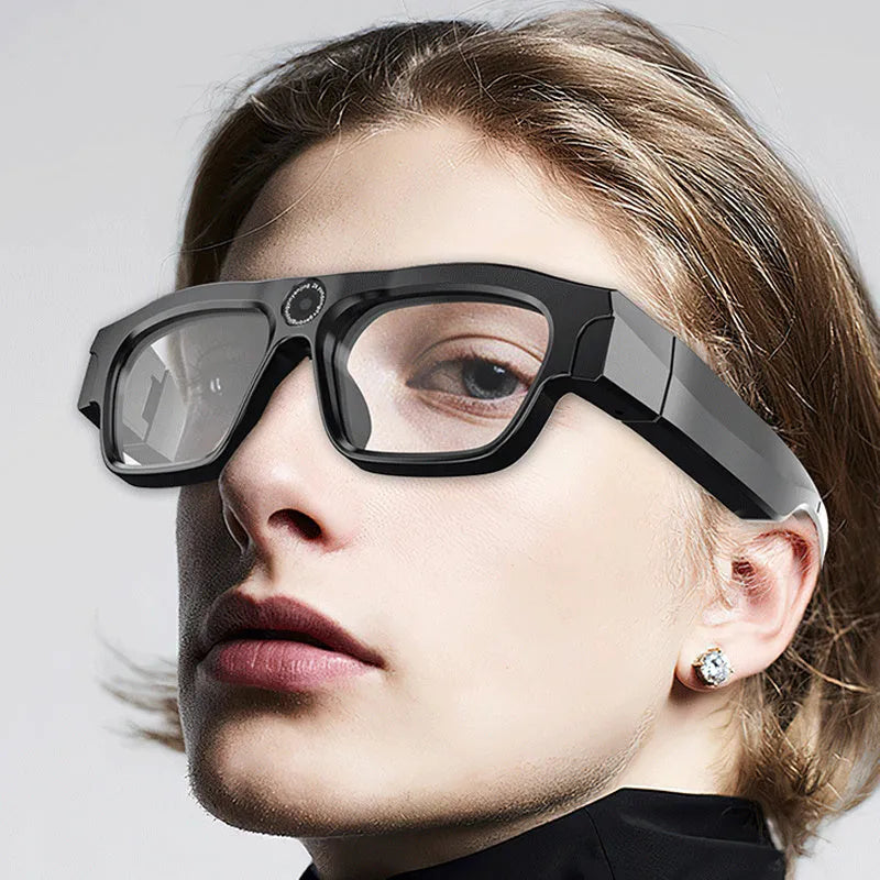 Black head-mounted smart Bluetooth glasses with a built-in camera for video recording on a table with accessories.