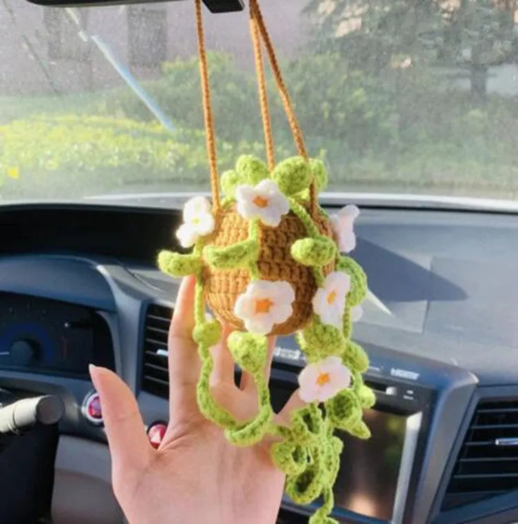 Green and white knitted wool car plant decoration hanging from a rope.
