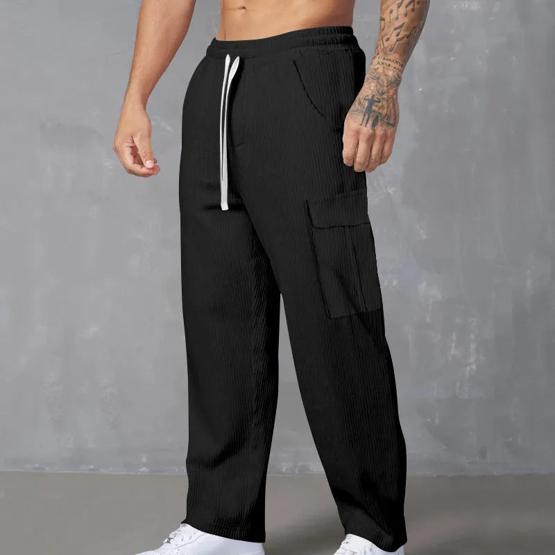 Man wearing loose-fitting navy blue corduroy cargo trousers with a straight leg and drawstring waist.