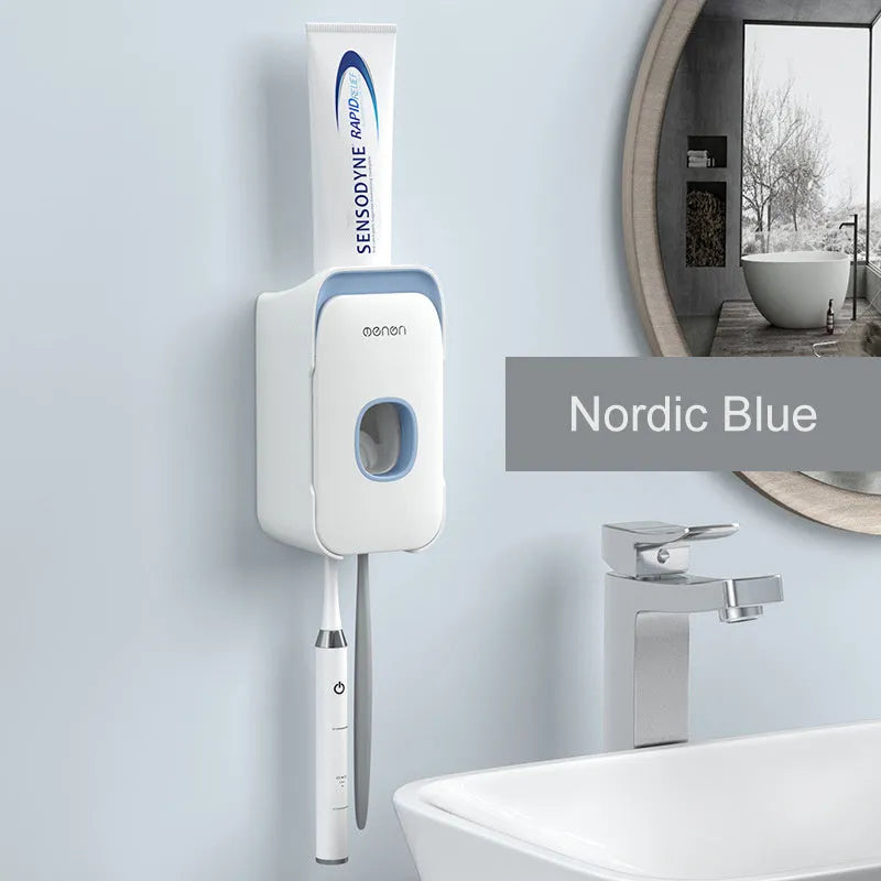 Blue automatic toothpaste dispenser mounted on a bathroom wall with a toothbrush below.