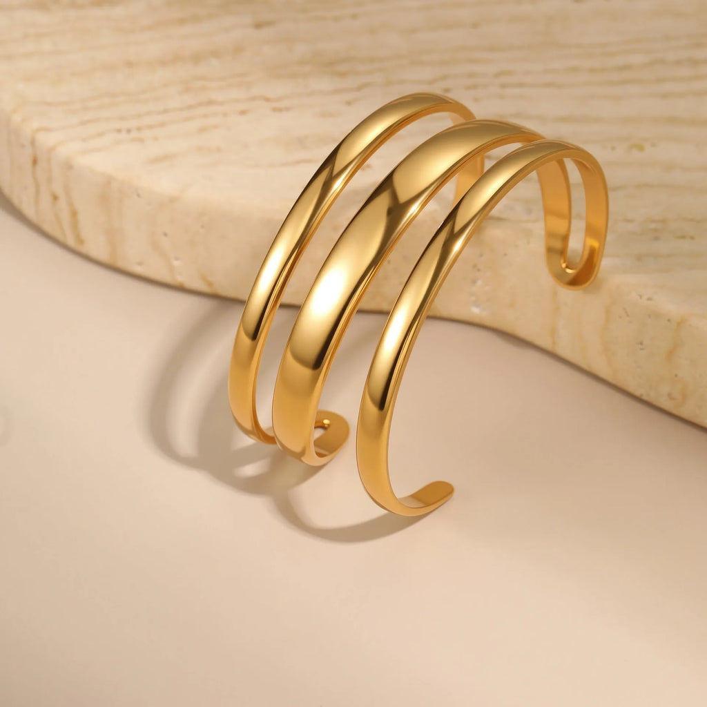 Stainless steel women's bracelet with geometric line design, shown in gold and steel finish options