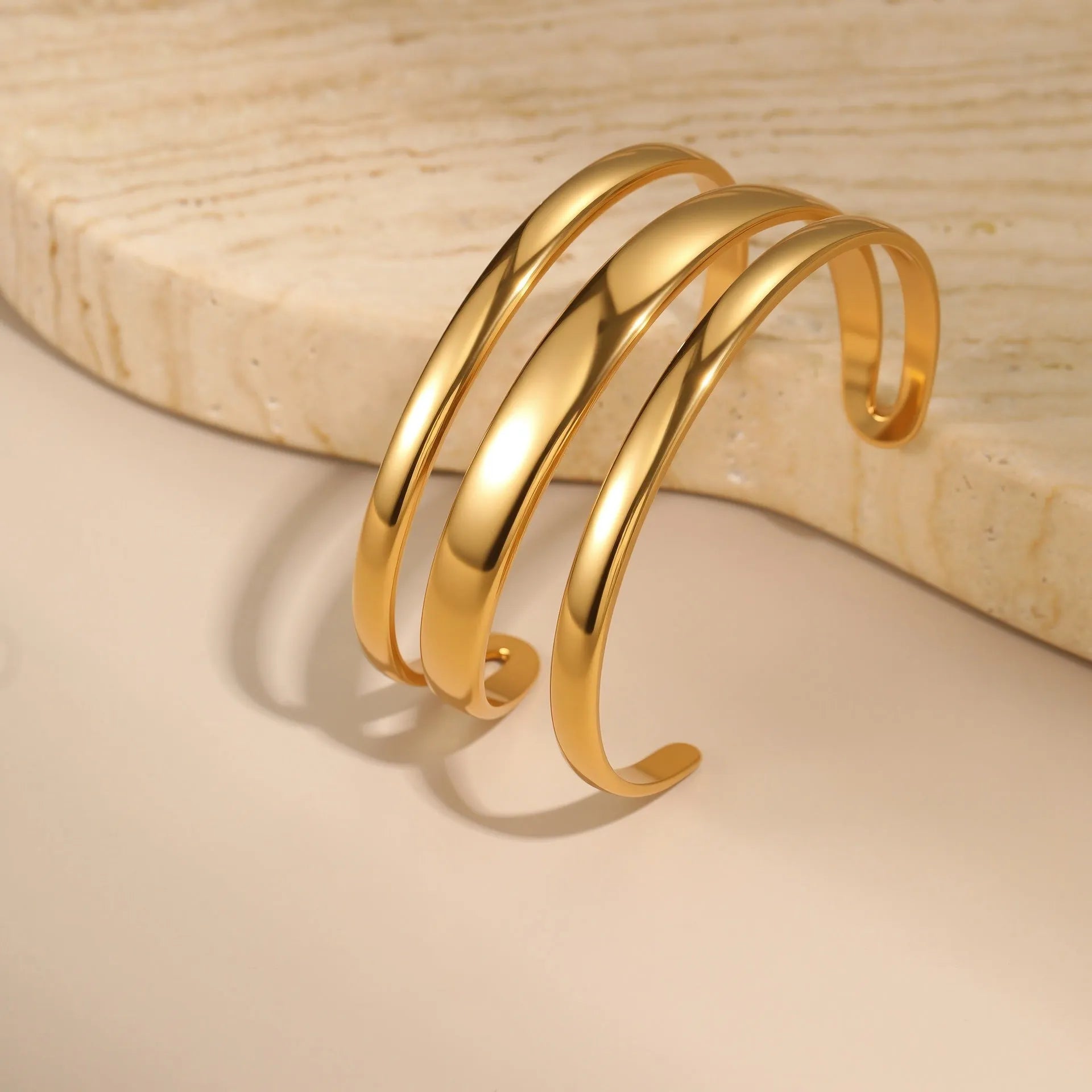 Stainless steel women's bracelet with geometric line design, shown in gold and steel finish options