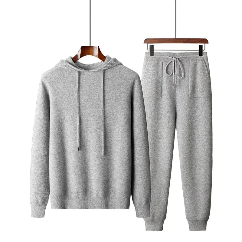 Man wearing a light grey hooded cashmere sweatshirt and matching long pants from a winter leisure set.