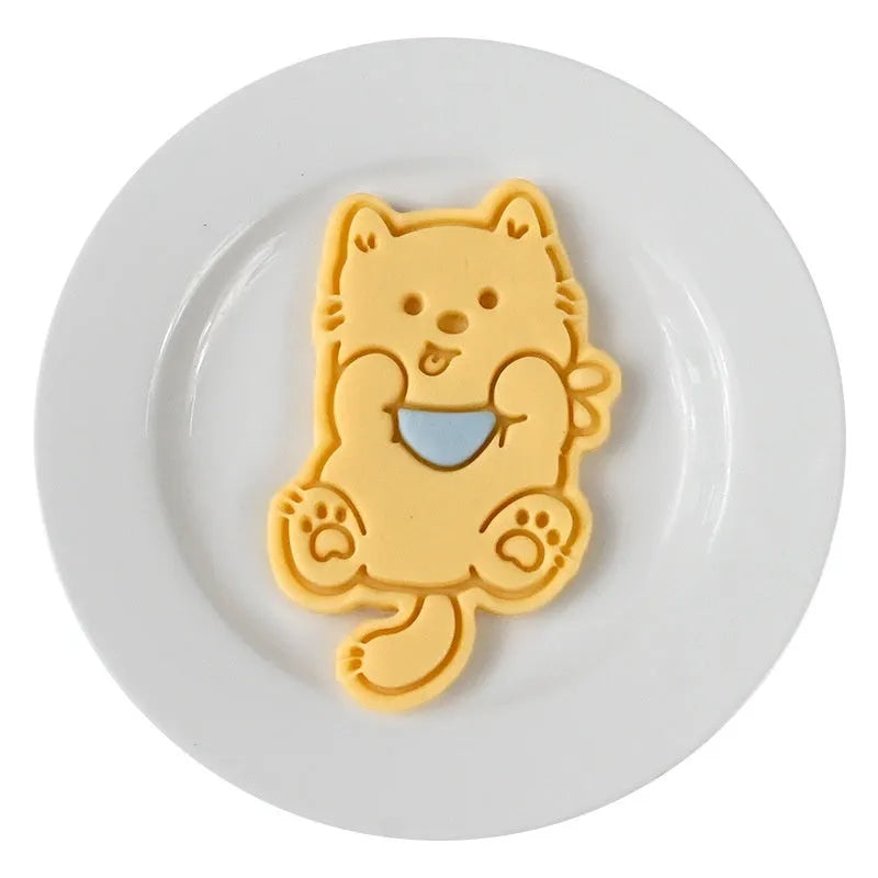Three-dimensional plastic biscuit mold showing cartoon puppy designs including birthday hat and swimming ring motifs