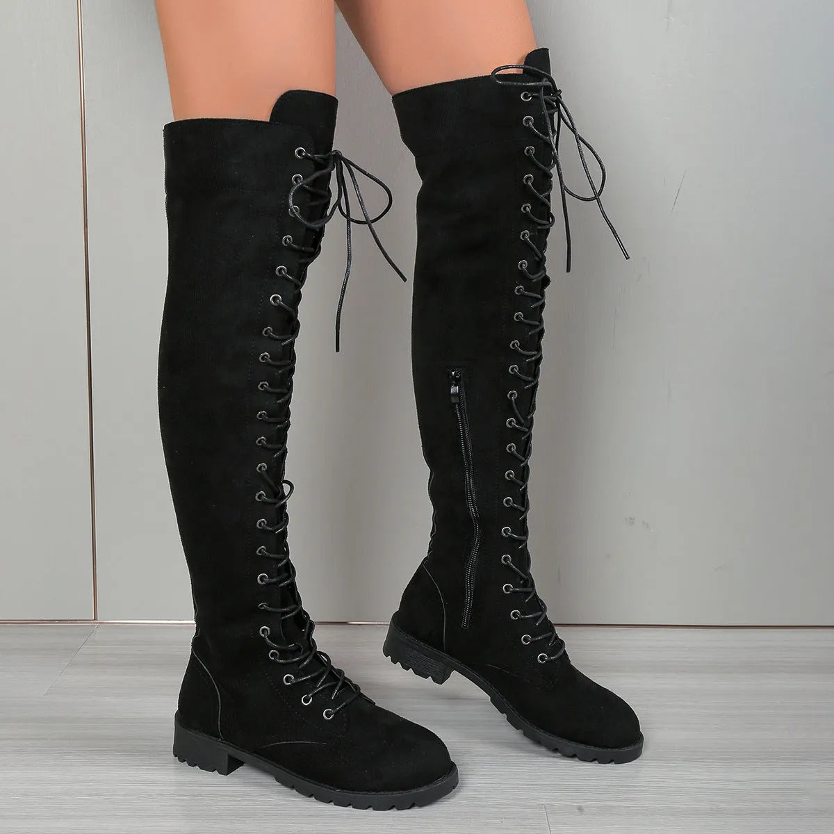 A pair of black lace-up over-the-knee boots with a round toe and flat rubber sole on a white background.