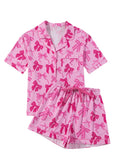 Pink women's pyjama set with bow print, featuring a top and trousers made from lightweight polyester fabric.