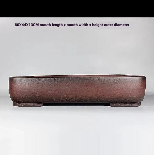 Large handmade antique rectangular purple clay flower pot on a table.