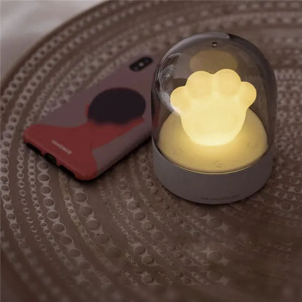 Grey cat paw shaped USB night light with rotating soft light and music box function on wooden desk