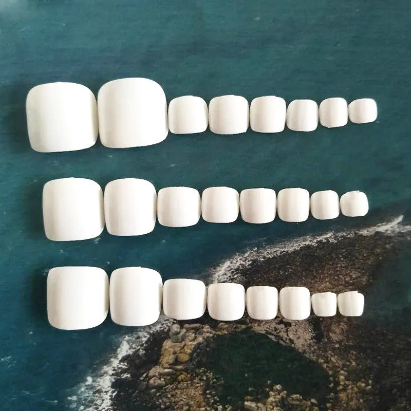 White false toe nails with a starry sky pattern, shown with a tube of nail glue.