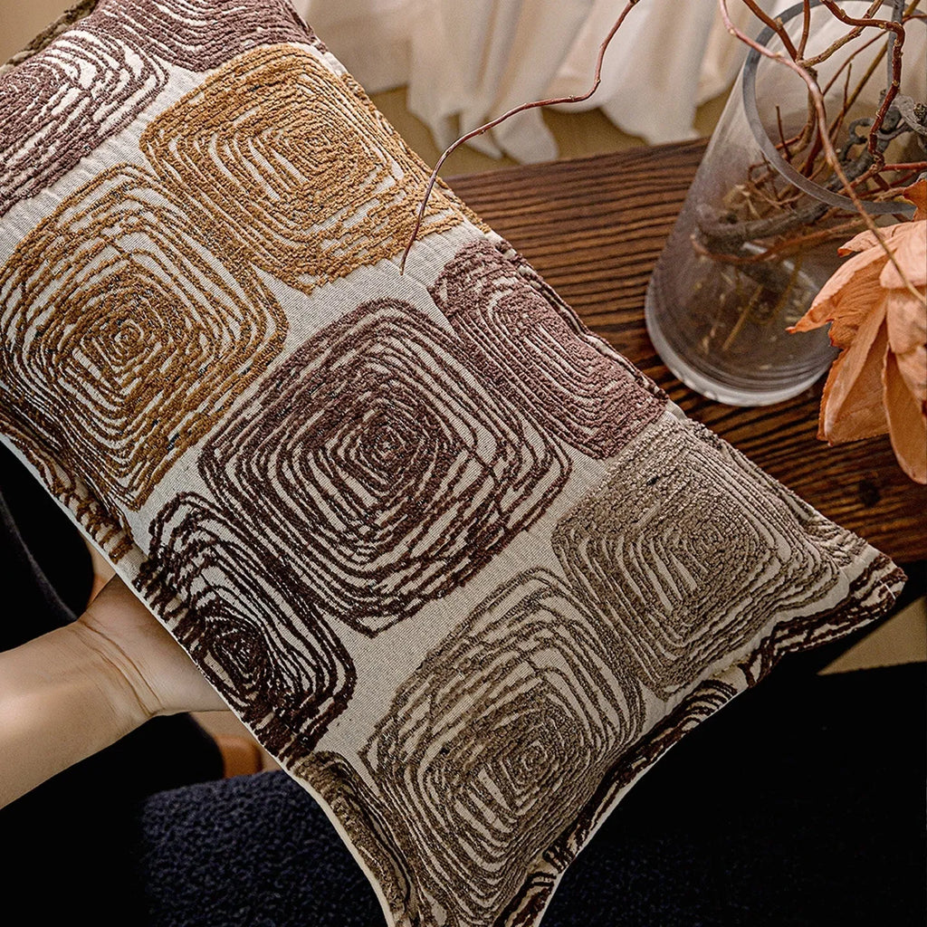 Cream and coffee-coloured abstract coil pattern on two pillow covers: one square, one rectangular.