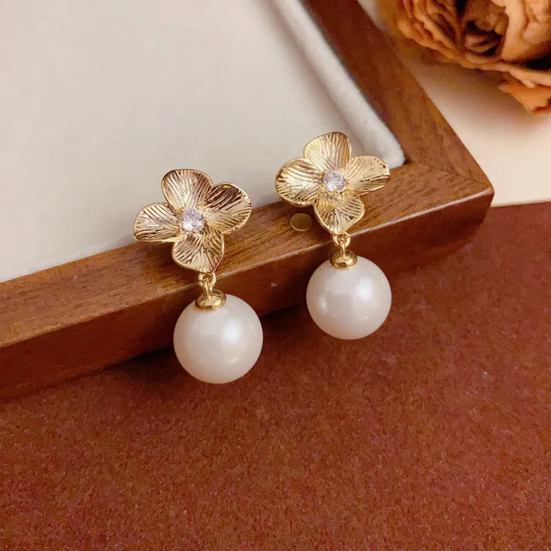 Pair of gold-plated copper earrings with metal petal design and faux pearl accents for women