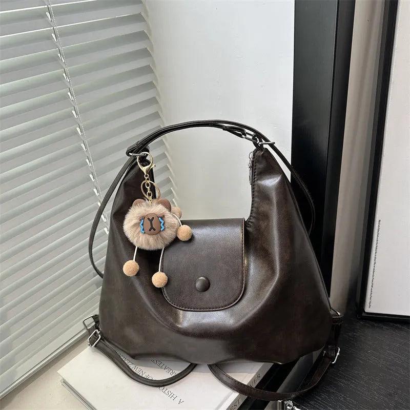 Textured PU leather commuter shoulder backpack in horizontal square shape with single strap and mobile phone compartment