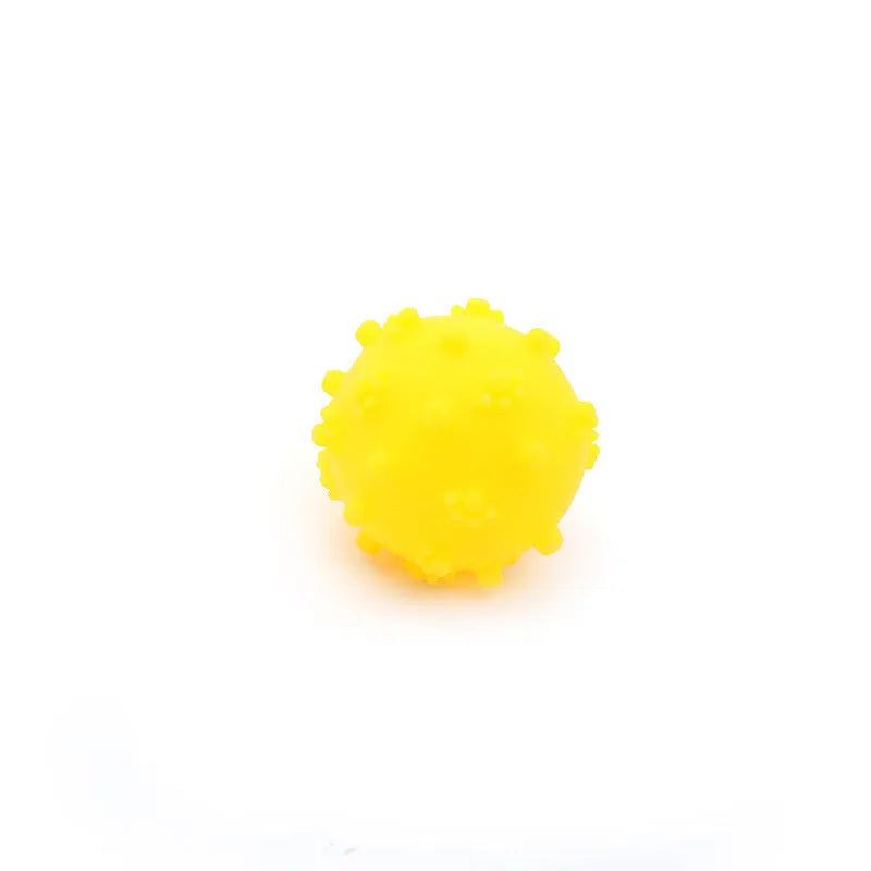 Bright blue, green, pink, and yellow spiked dog balls with paw print dimples on a white background.