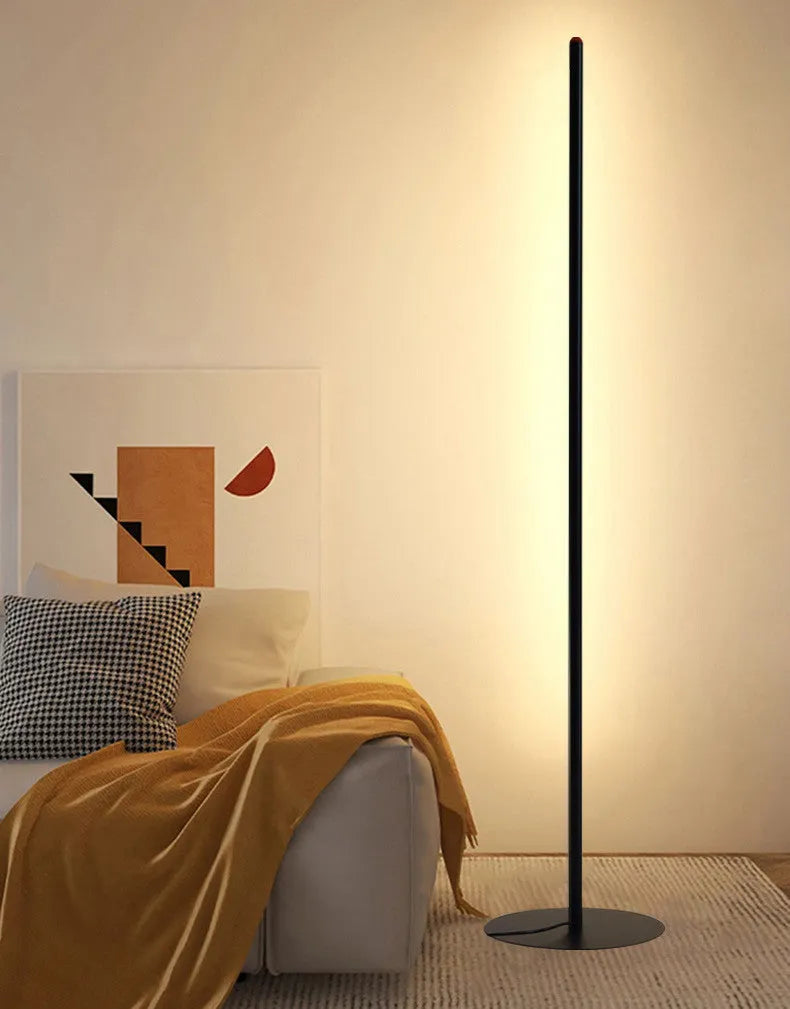 Vertical aluminium alloy floor lamp with a simple modern design, shown in a living room setting.