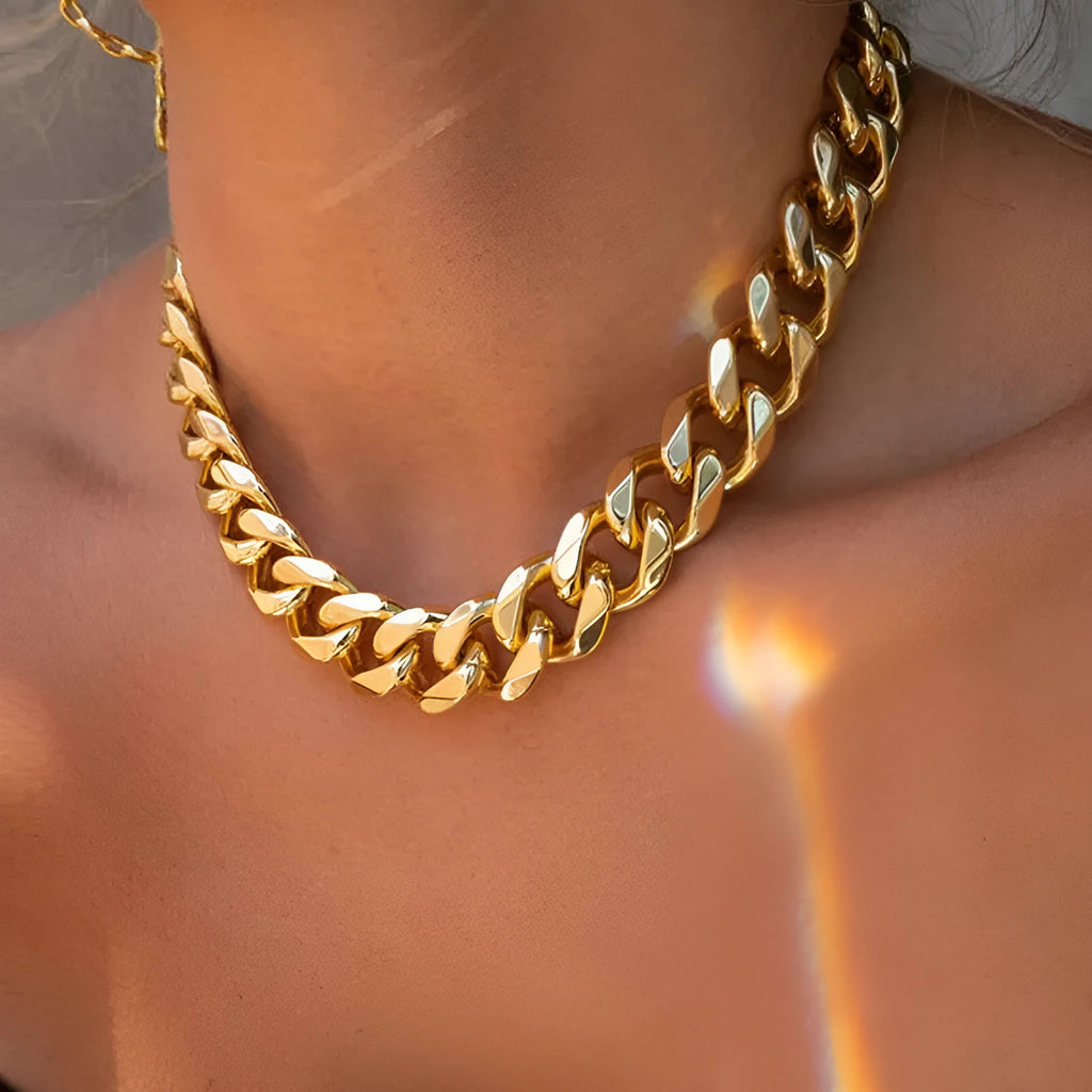 Gold coloured thick chain necklace for women on a white background.
