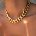 Gold coloured thick chain necklace for women on a white background.
