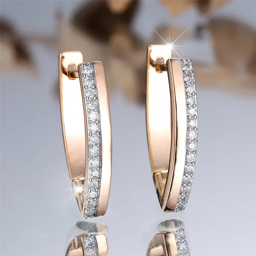 Geometric V-shaped women's earrings in champagne gold with white diamond accents on a copper base.