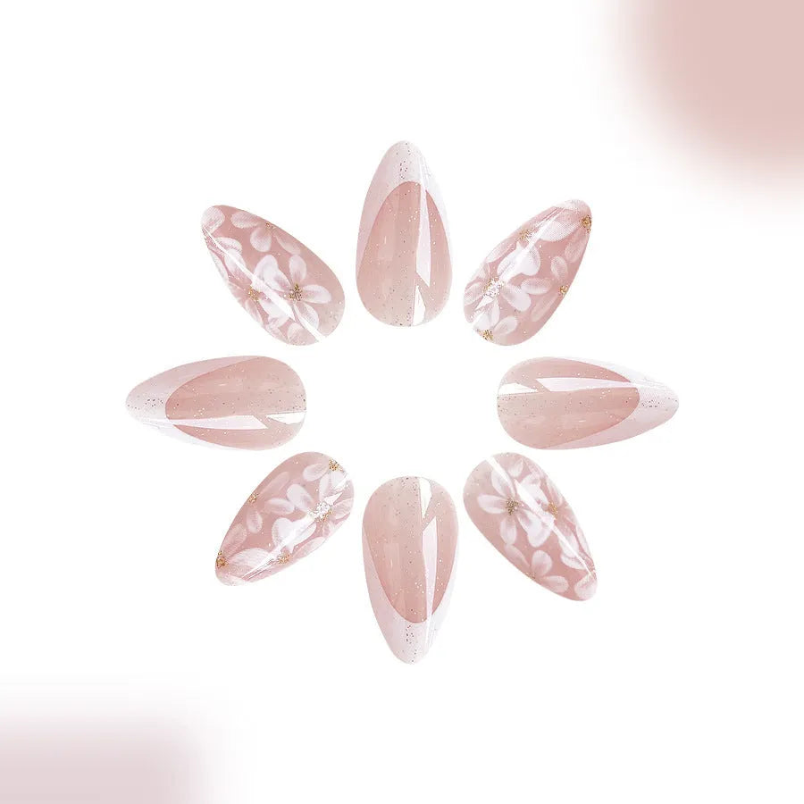 Short almond-shaped false nails with French style tips and glittering pink powder flowers on a white background.