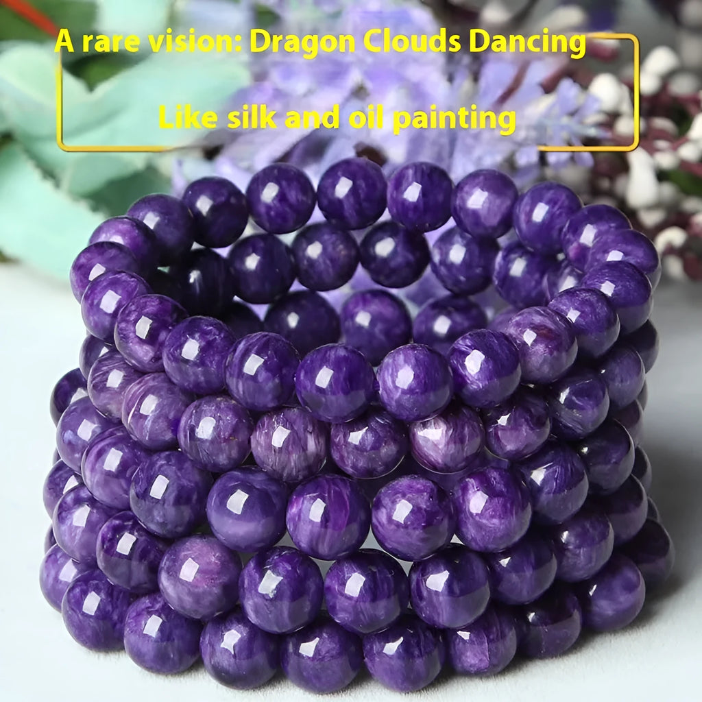 Natural transparent charoite crystal bead bracelet with platinum clasp on a wrist, showing violet and black swirled patterns.