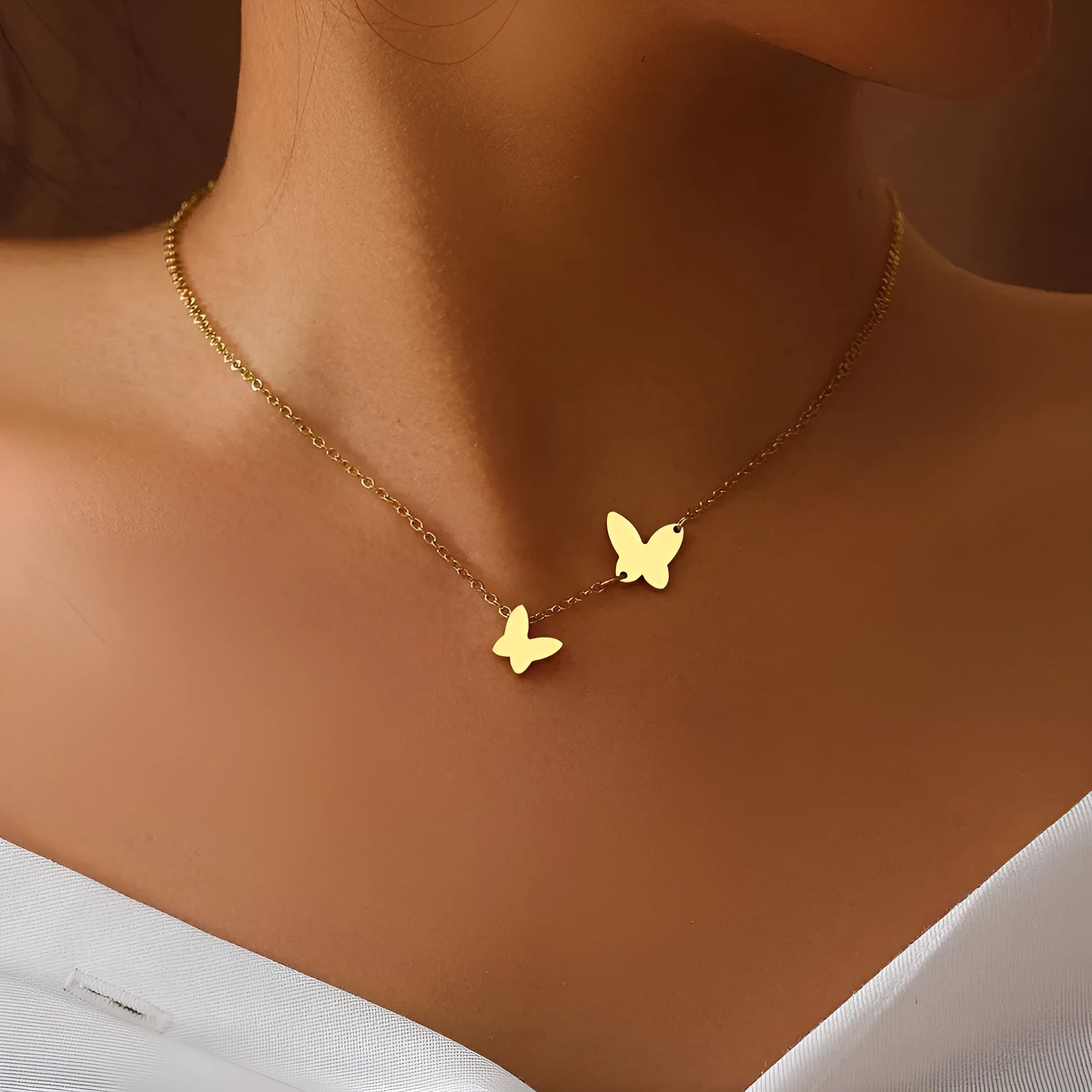 Butterfly pendant necklace in stainless steel with 18K gold electroplated finish on a white background