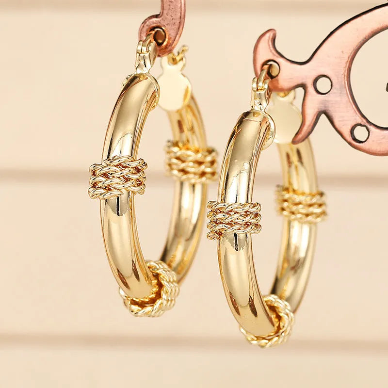 Geometric golden copper earrings with ear clip fastening showing ring and line design elements