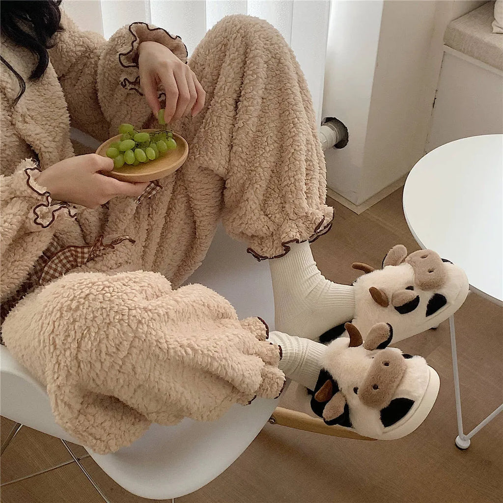 White cartoon cow plush slippers for women with a textured anti-slip sole.