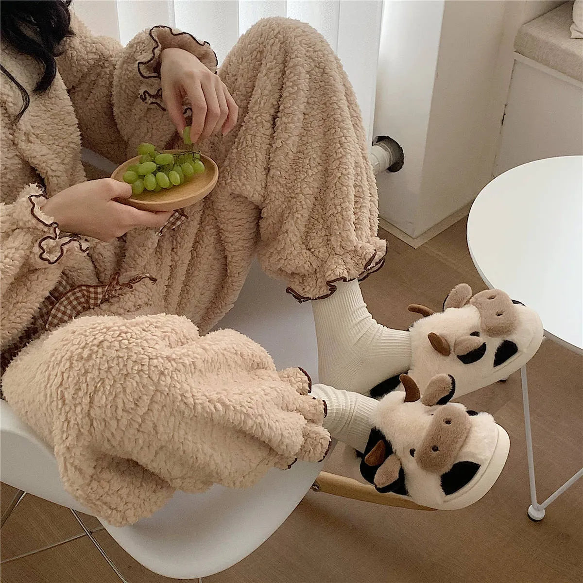 White cartoon cow plush slippers for women with a textured anti-slip sole.