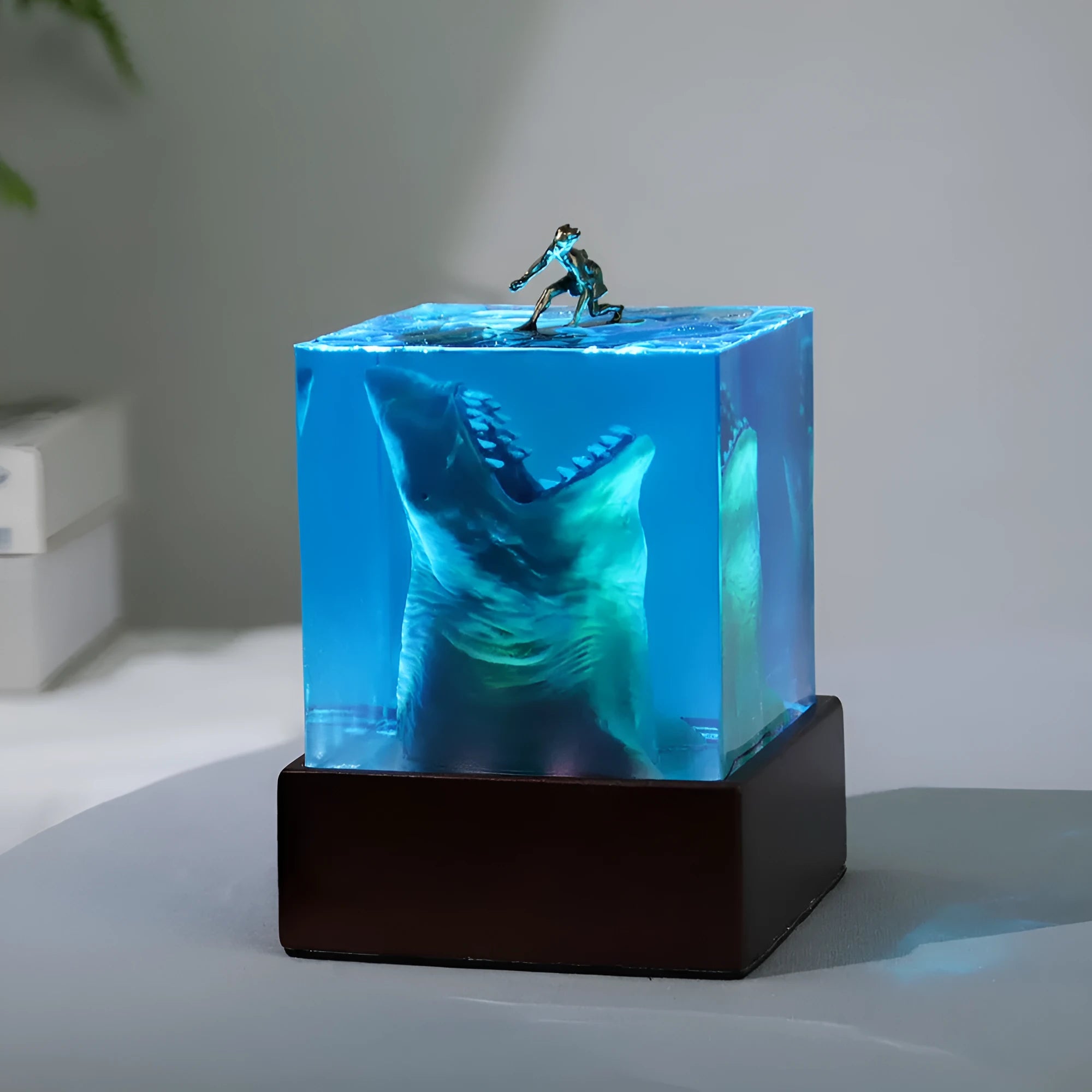 Clear epoxy resin ornament with a detailed shark surfing scene inside, shown next to its integrated lamp holder.