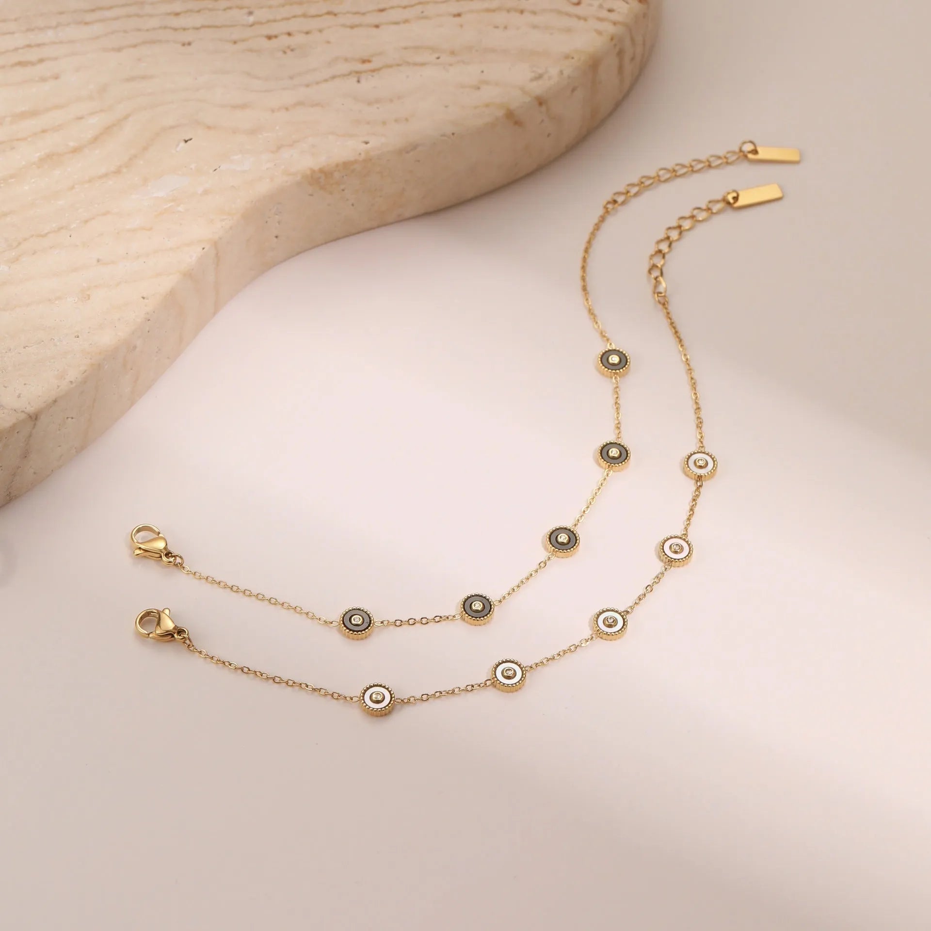Close-up of a women's geometric fritillary pattern bracelet and necklace set in gold-plated stainless steel.