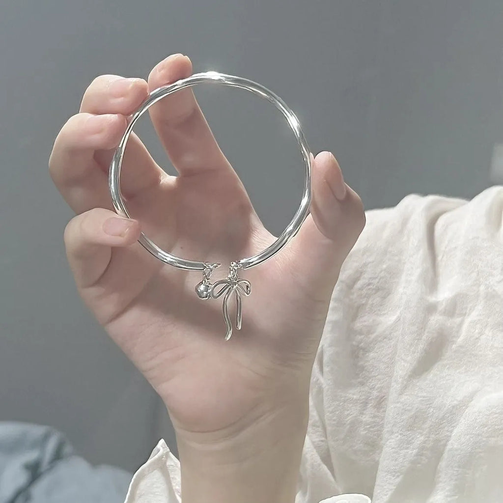 Silver bow adjustable bracelet with zinc alloy construction and electroplated finish.