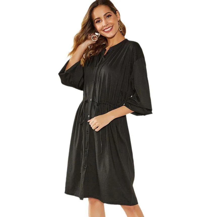 Women's black A-line dress with elastic waist, long sleeves, and a cinching belt on a mannequin.