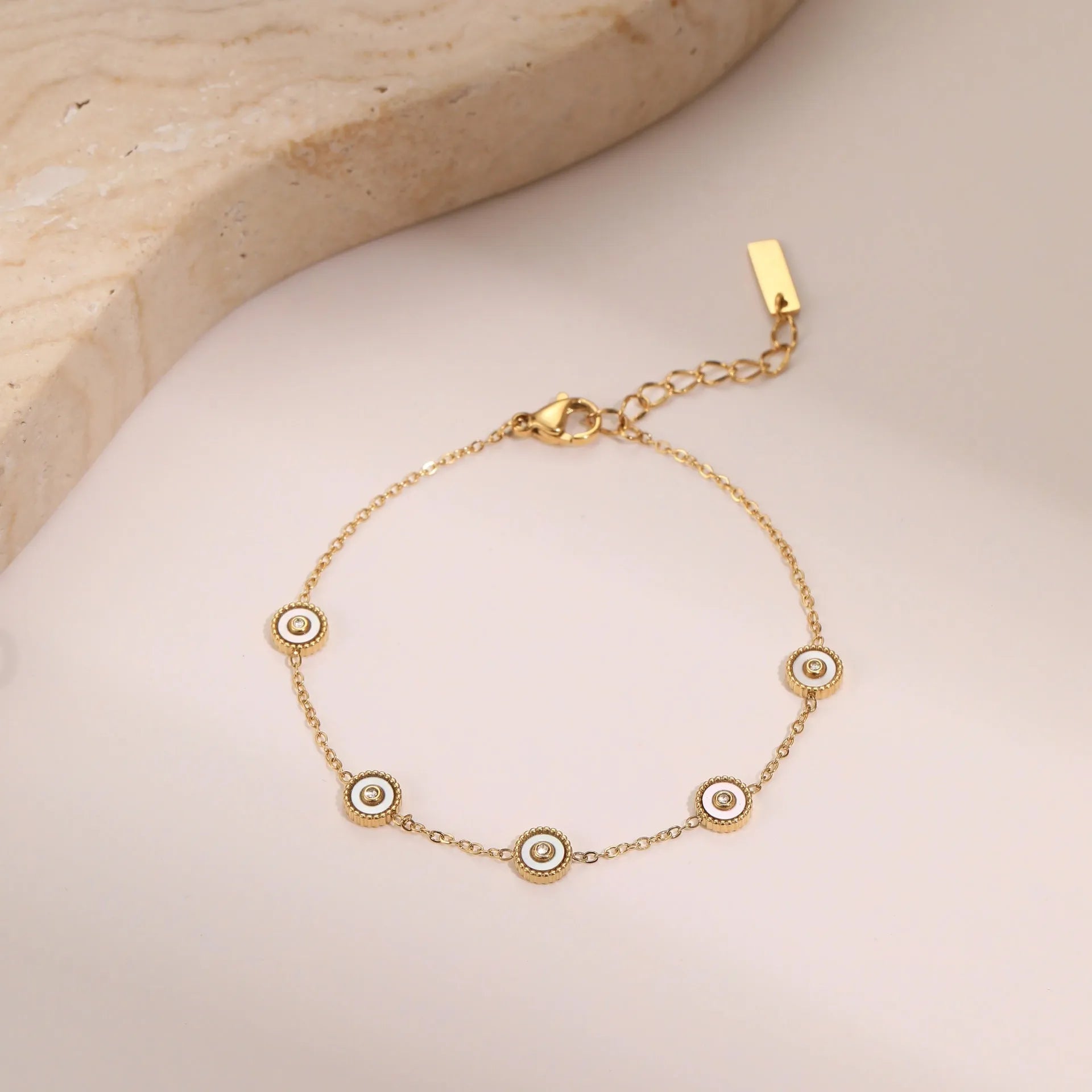 Close-up of a women's geometric fritillary pattern bracelet and necklace set in gold-plated stainless steel.