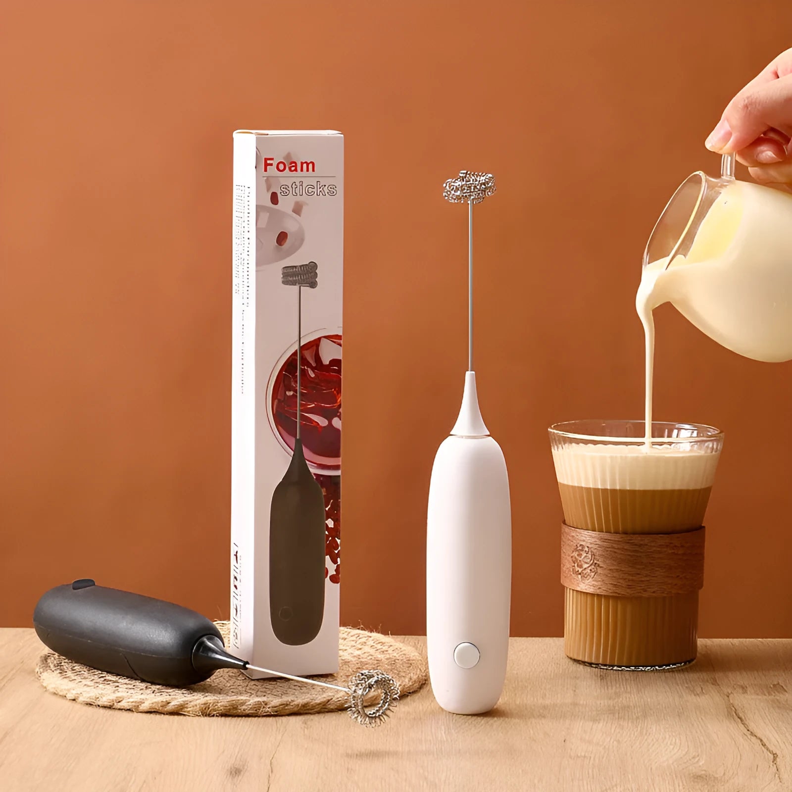 Black and white handheld electric milk frother with blending function on kitchen counter