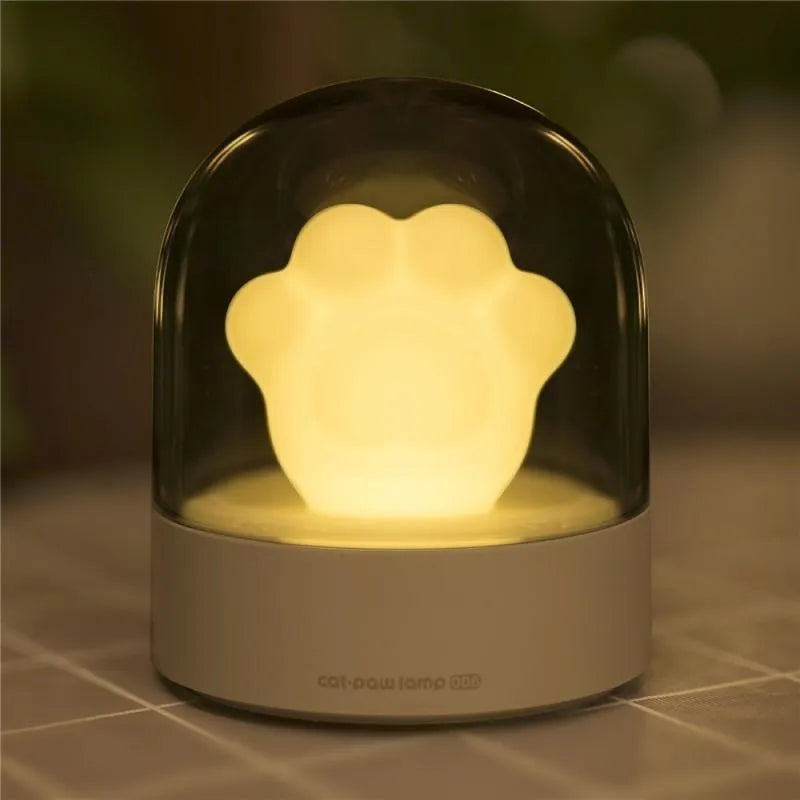 Grey cat paw shaped USB night light with rotating soft light and music box function on wooden desk