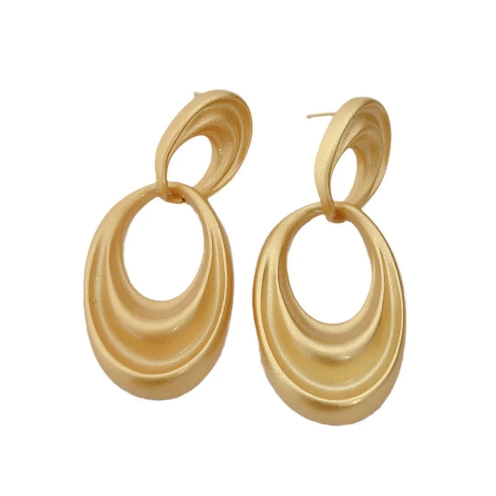 Plain gold coloured U-shaped double circle earrings with a French retro style on a copper background.