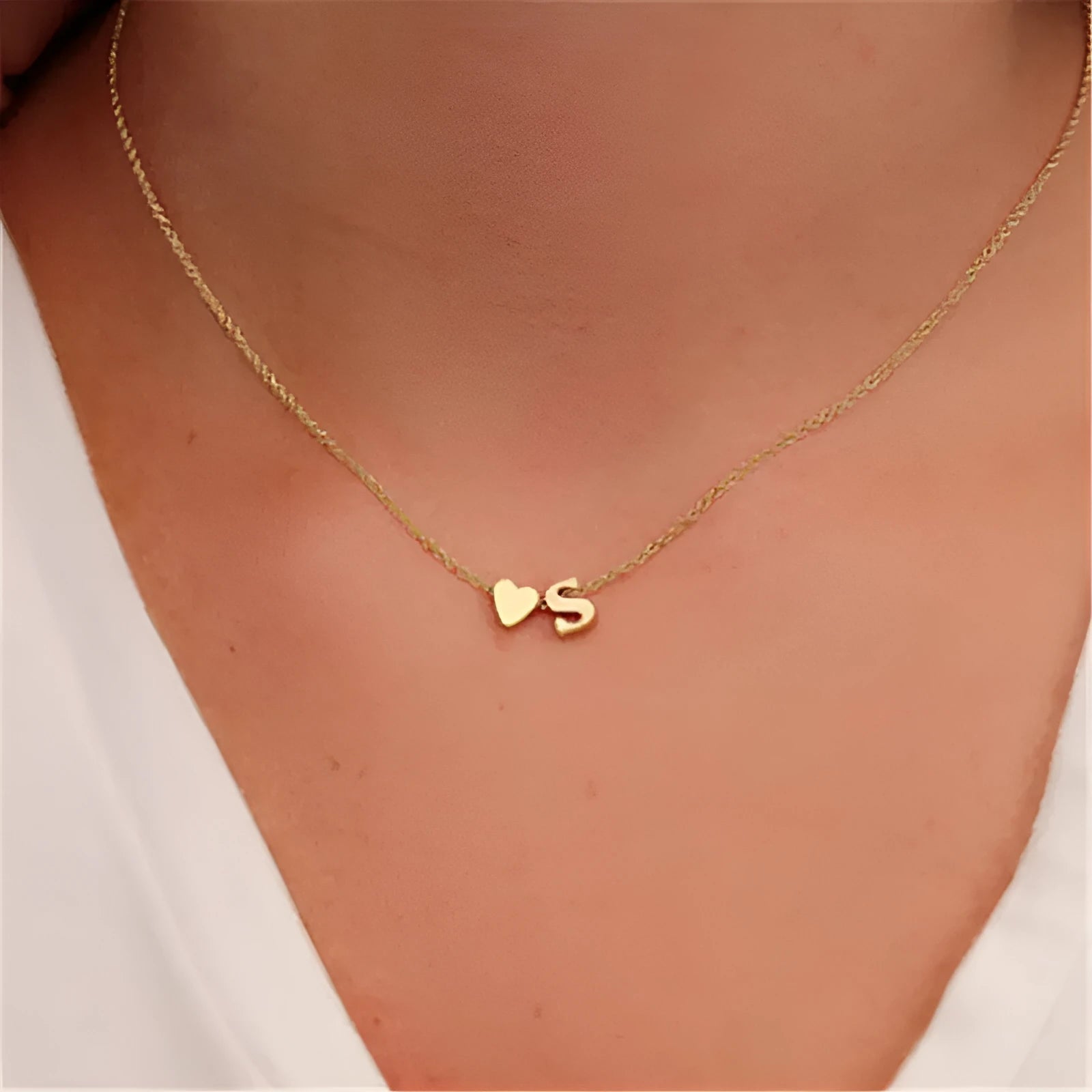 Gold alloy peach heart pendant necklace with a letter detail on a delicate chain.