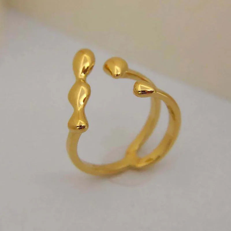 Open circle brass fashion ring with spherical beads in gold tone on a hand.