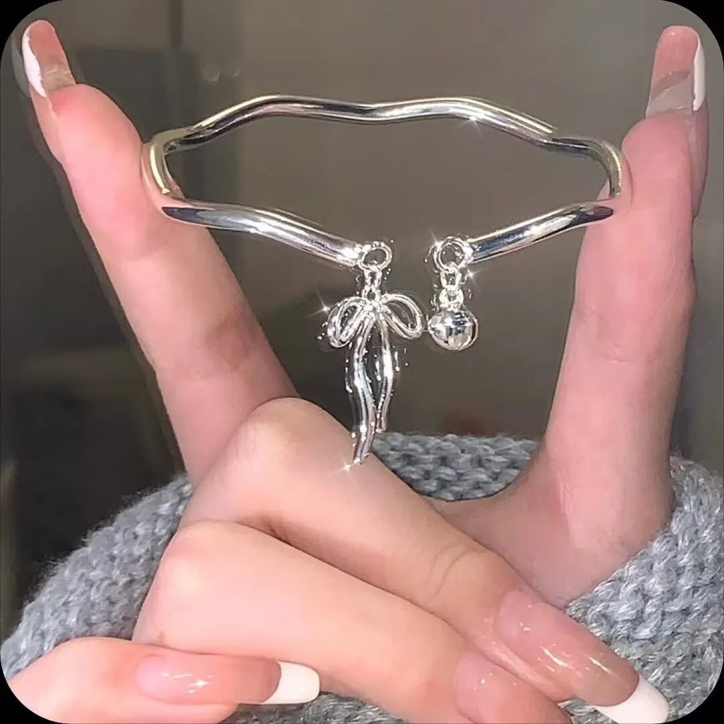 Silver bow adjustable bracelet with zinc alloy construction and electroplated finish.