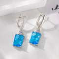 A pair of square-shaped gold and silver electroplated copper earrings on a flat surface.