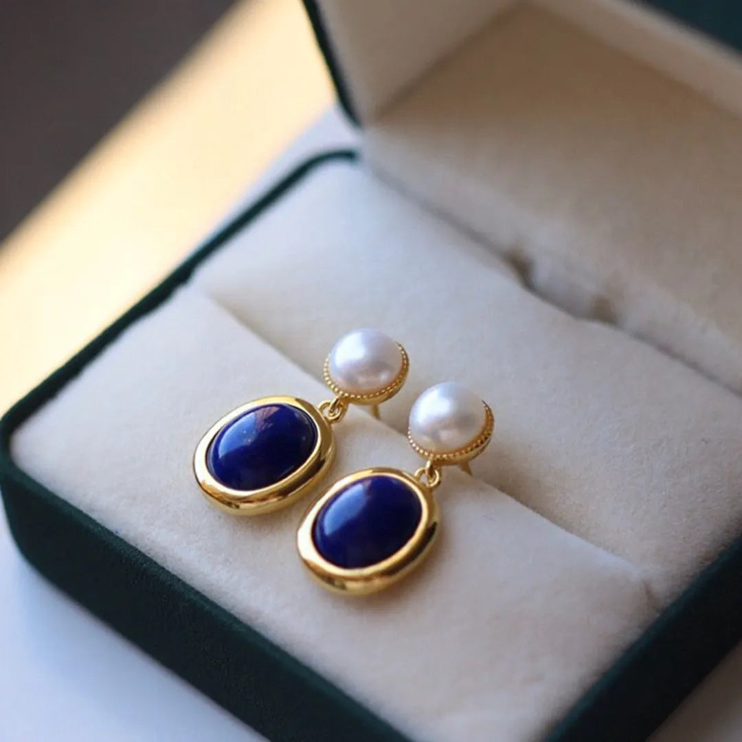 A pair of simple sterling silver stud earrings with blue lapis lazuli pearls and auspicious pattern details.