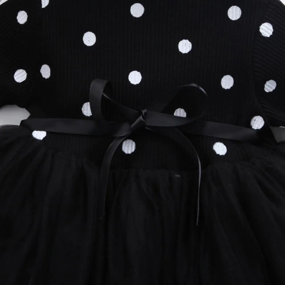 Baby girl in a long sleeve black tutu lace dress for a christening or birthday party.