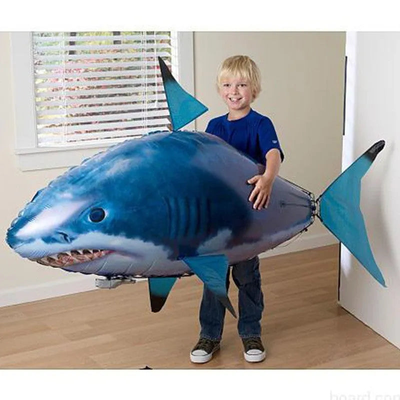 Large remote control shark-shaped helium balloon toy floating indoors with a remote.