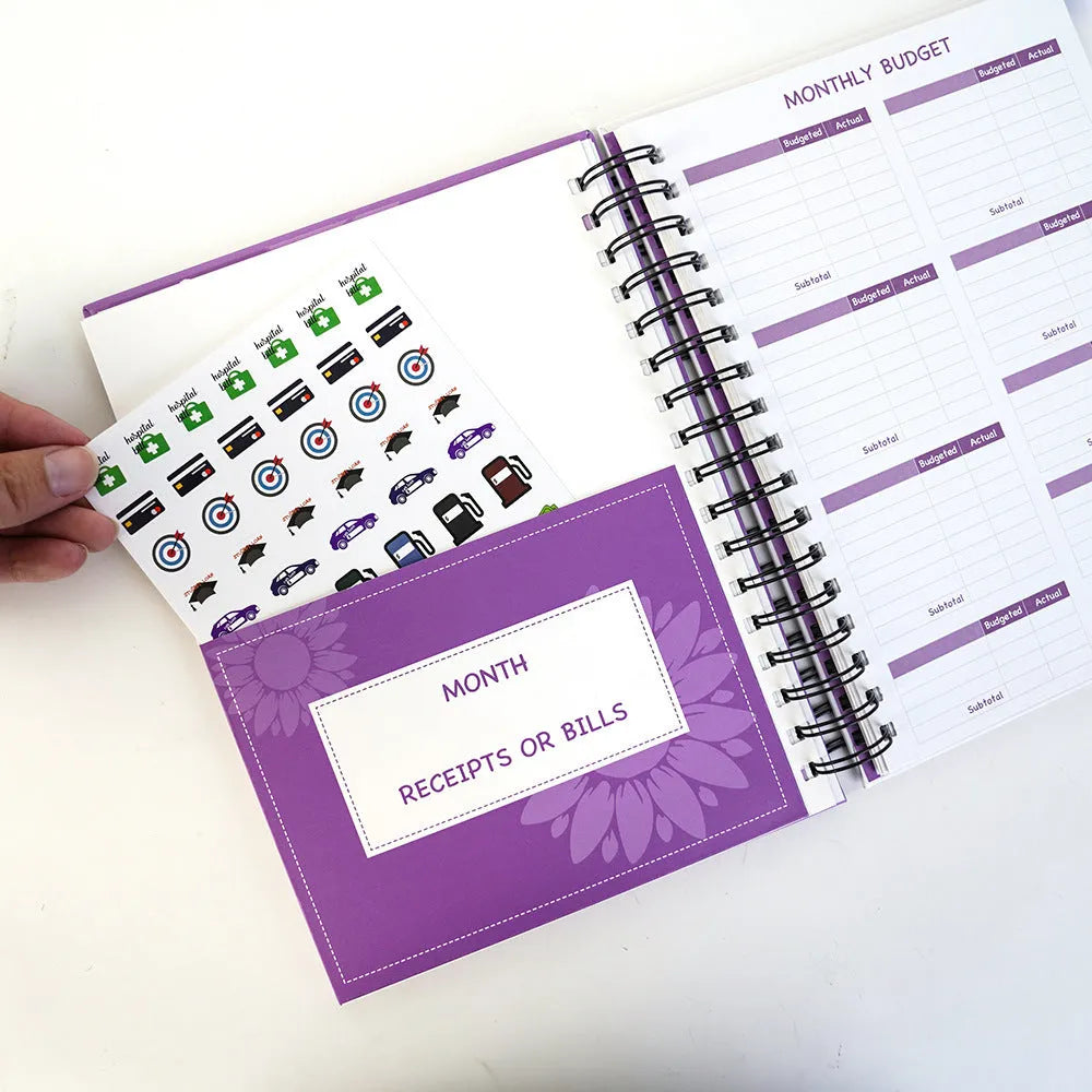 Purple coil-bound budget notebook with financial planning stickers and paper clips for monthly money management