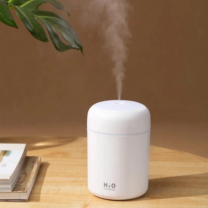 Pink, white or navy blue USB mini humidifier with colourful lights on desk surface
